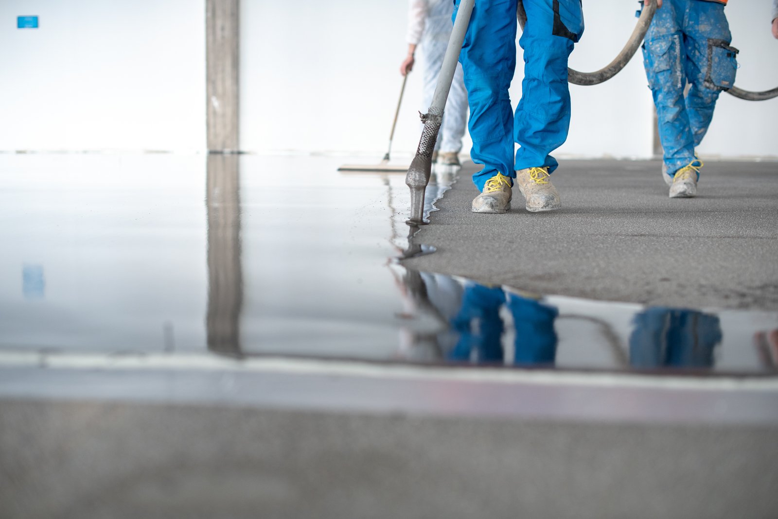Workers pouring self-leveling compound onto a floor