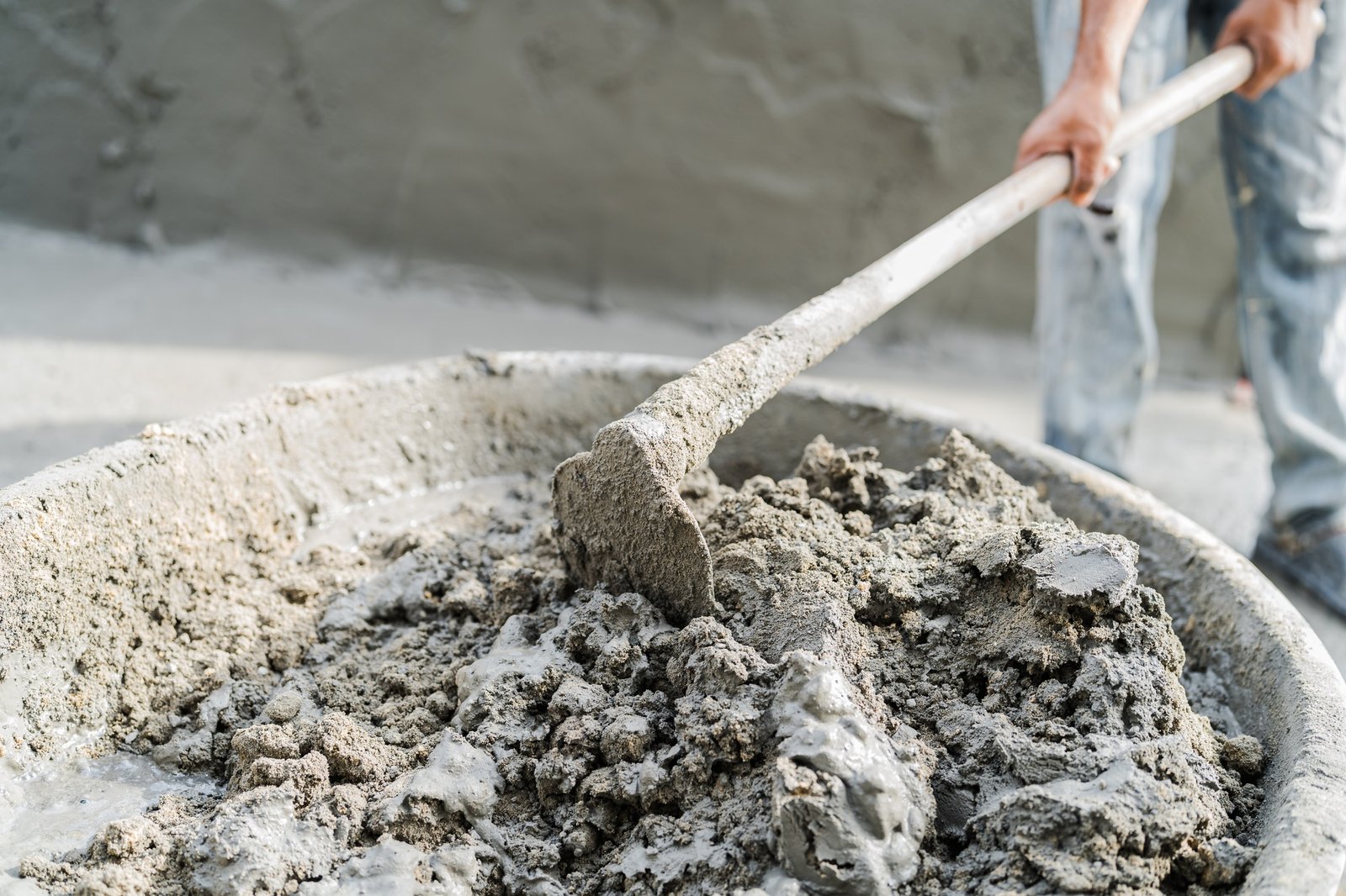 Worker mixing cementitious mortar constituents at a job site