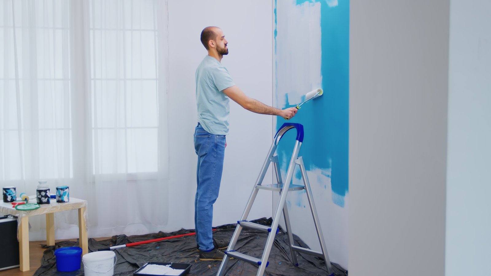 Worker applying paint to an interior wall