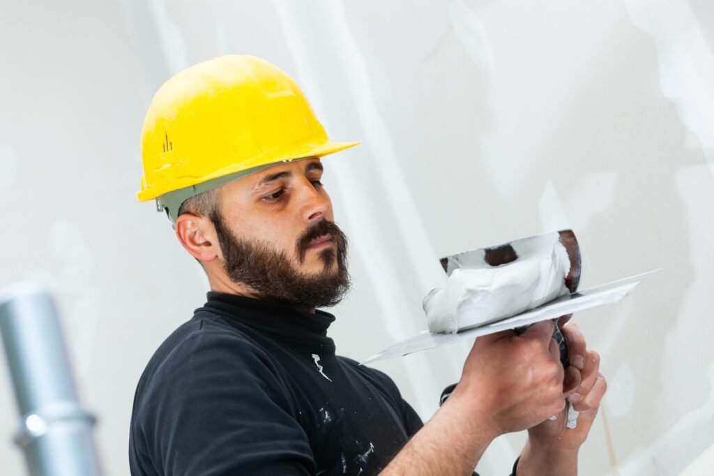 worker plastering gypsum board wall.
